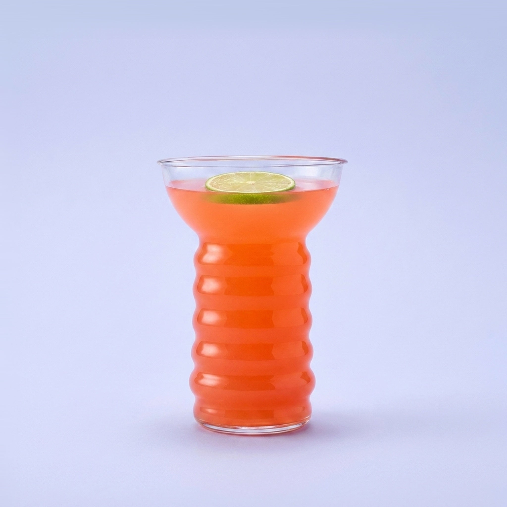 Bar Professional Pearl Diver cocktailglas 48 cl gevuld met koraaloranje tropische cocktail en limoenschijf op pastelblauwe studioachtergrond